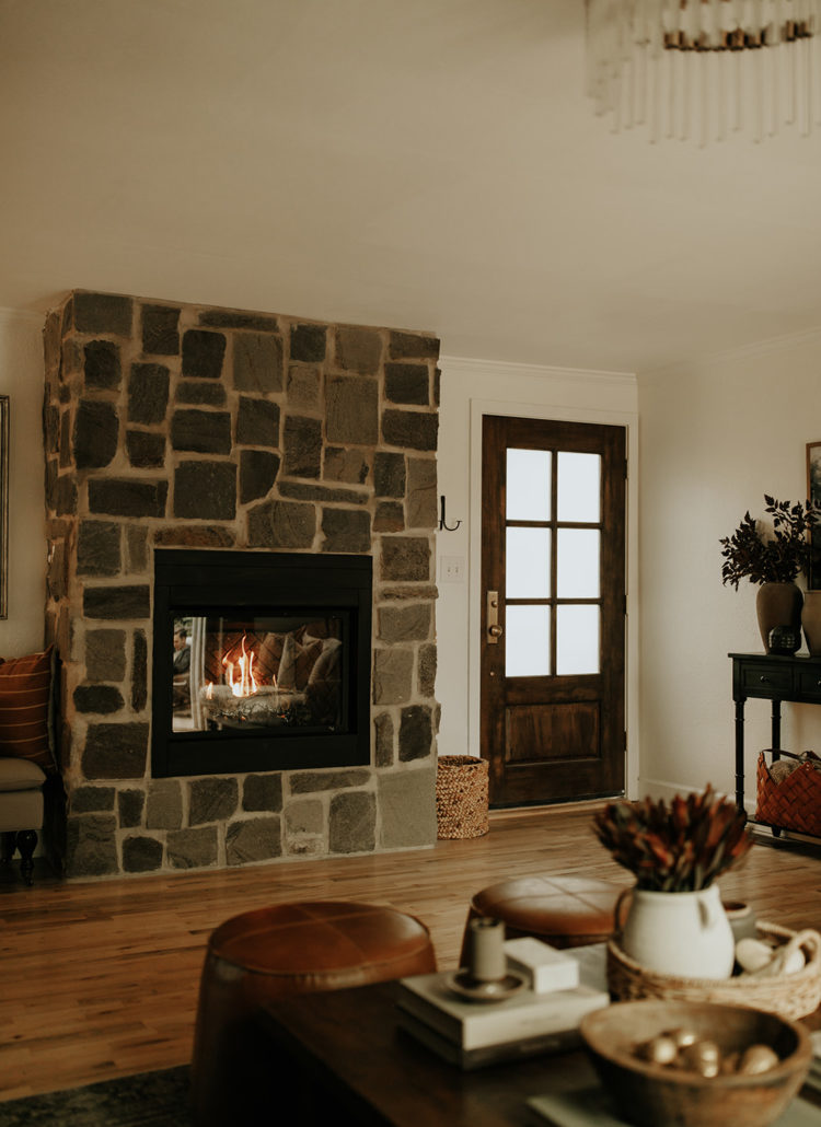 An indoor setting with a coffee table, fireplace with brick and wood front door