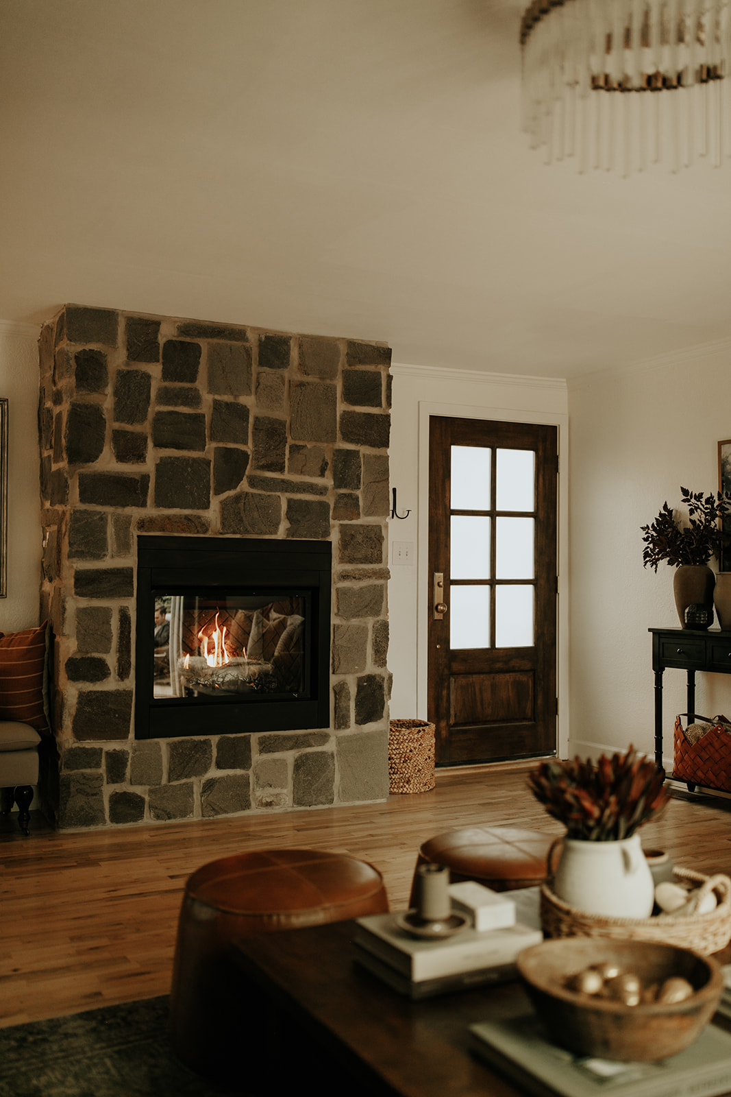 An indoor setting with a coffee table, fireplace with brick and wood front door
